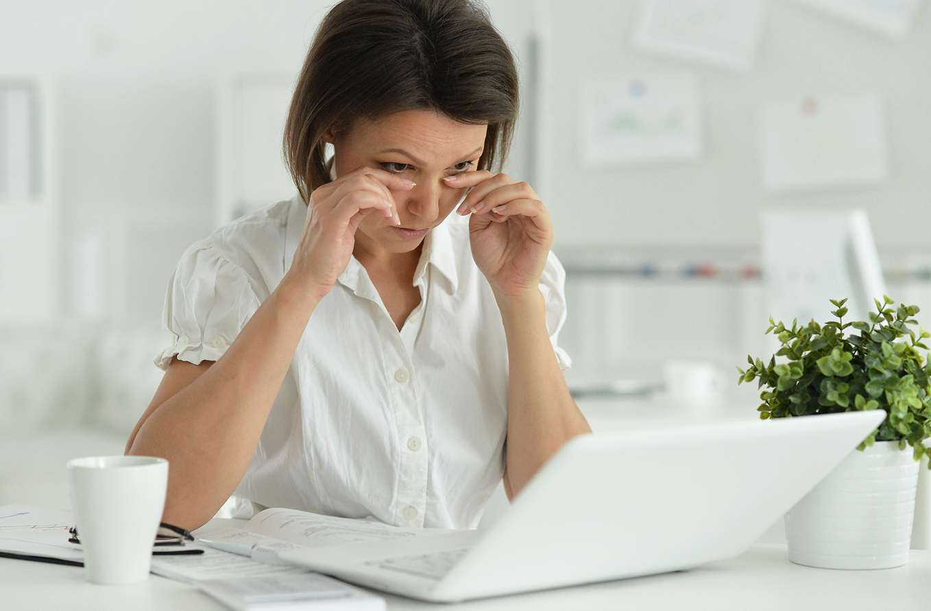Joven frotándose los ojos frente a un ordenador