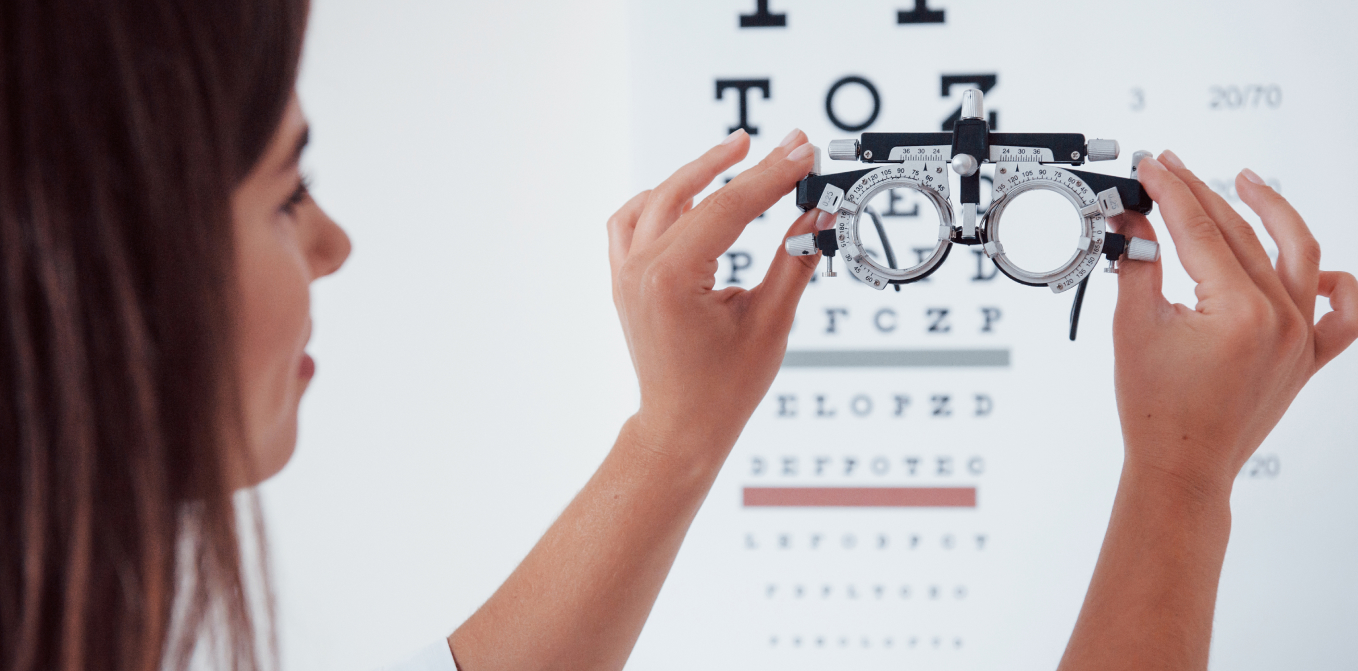 optometrista fent una prova de visió amb foròpter davant d’una cartilla optomètric