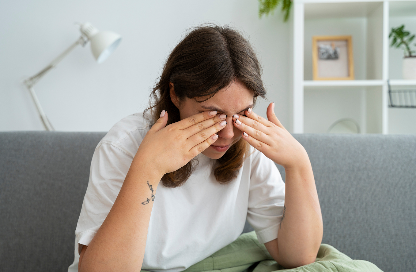 Mujer frotándose los ojos en casa por molestias oculares causadas por la alergia primaveral.