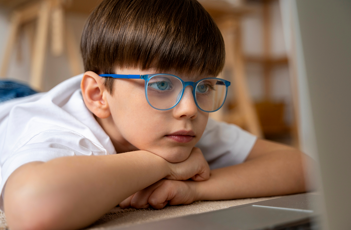 Niño con gafas leyendo en una biblioteca, en un contexto escolar.